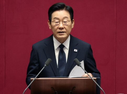 O presidente da Coreia do Sul fala ao microfone à frente de um fundo vermelho