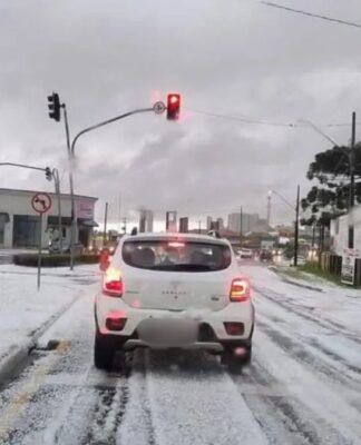 Carros estão parados no sinal vermelho do semáforo, sobre asfalto coberto de gelo