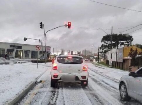 Carros estão parados no sinal vermelho do semáforo, sobre asfalto coberto de gelo