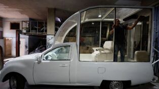 Imagem do Papamóvel (picape branca) sendo convertida por um mecânico