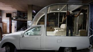 Imagem do Papamóvel (picape branca) sendo convertida por um mecânico