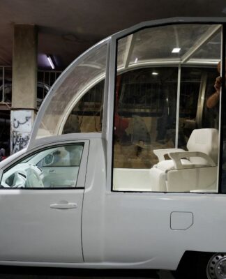 Imagem do Papamóvel (picape branca) sendo convertida por um mecânico