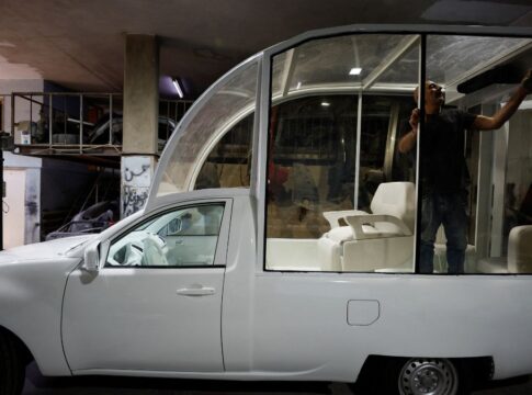 Imagem do Papamóvel (picape branca) sendo convertida por um mecânico