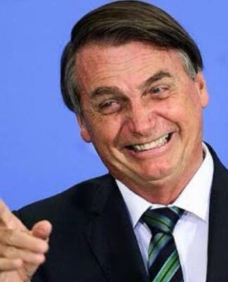Foto antiga de Jair Bolsonaro, quando ainda era presidente, sorrindo e apontando com o dedo para fora da câmera