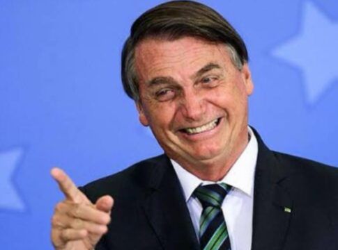 Foto antiga de Jair Bolsonaro, quando ainda era presidente, sorrindo e apontando com o dedo para fora da câmera
