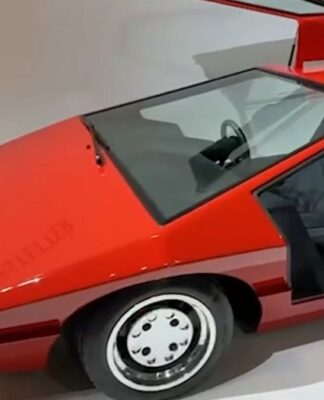 Foto de um carro esportivo vermelho de 1980, com bancos pretos e rodas de cor prateada