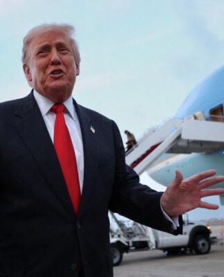 Donald Trump faz gesto com as mãos em frente a um avião