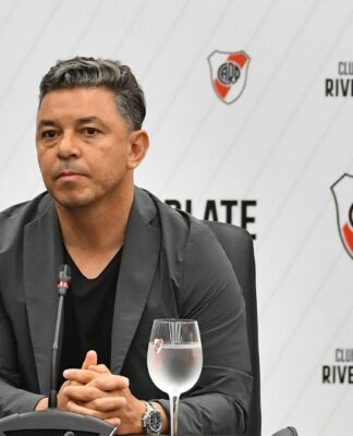 Técnico Gallardo, do River Plate, sentado com um copo de água ao seu lado, durante o anúncio de sua renovação de contrato