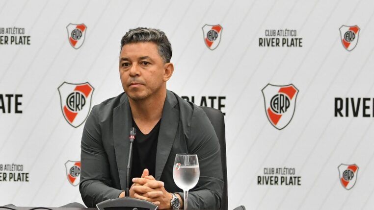 Técnico Gallardo, do River Plate, sentado com um copo de água ao seu lado, durante o anúncio de sua renovação de contrato
