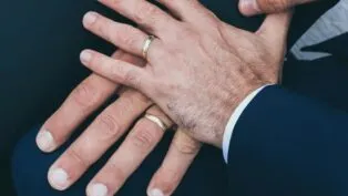 Duas mãos masculinas com alianças