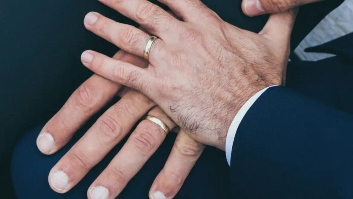 Duas mãos masculinas com alianças