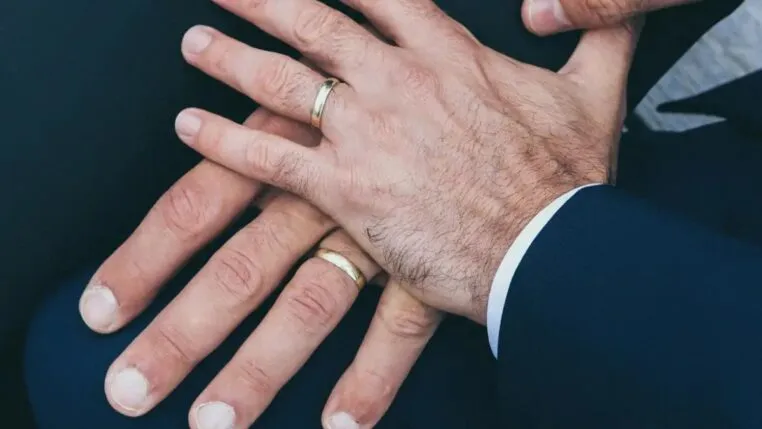Duas mãos masculinas com alianças