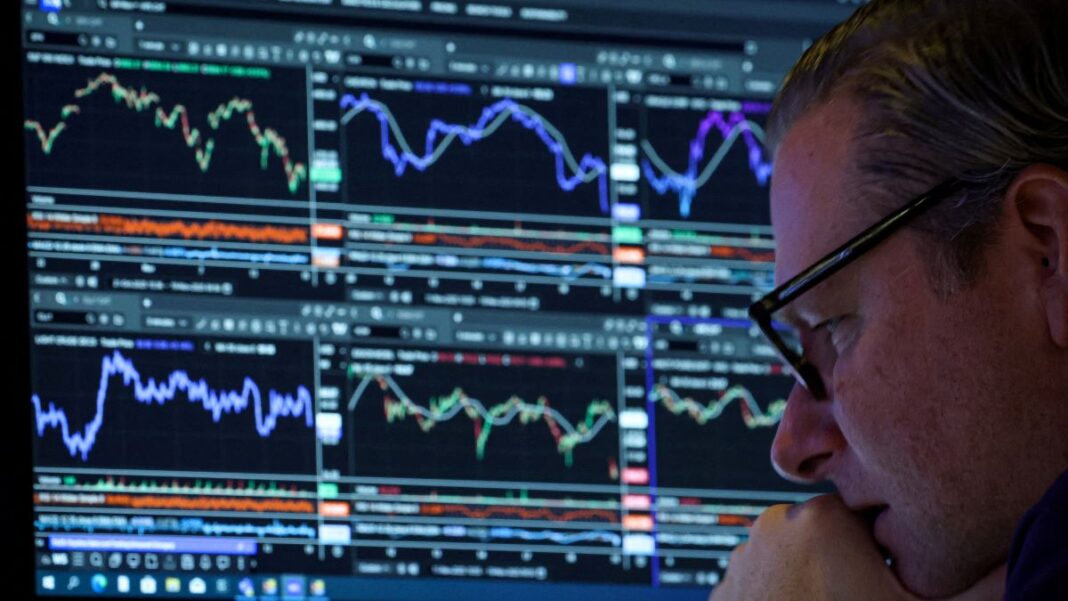 Homem de óculos, ao canto da imagem, analisando uma série de gráficos indicativos de bolsa de valores