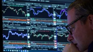 Homem de óculos, ao canto da imagem, analisando uma série de gráficos indicativos de bolsa de valores