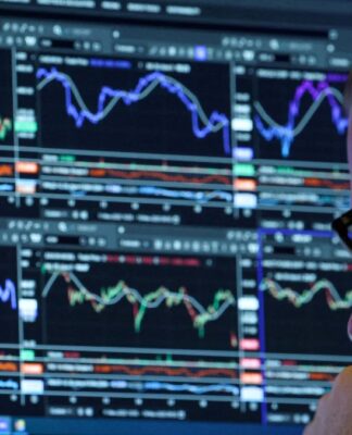 Homem de óculos, ao canto da imagem, analisando uma série de gráficos indicativos de bolsa de valores