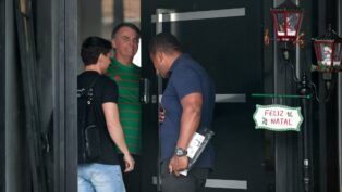 Jair Bolsonaro veste camisa verde na entrada de sua casa