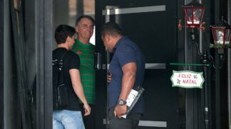 Jair Bolsonaro veste camisa verde na entrada de sua casa