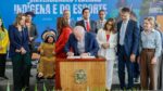 Lula assinando projeto de lei em palanque com ministros em volta