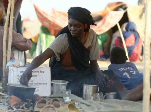 Uma mulher sudanesa deslocada prepara chá enquanto outras pessoas se reúnem e sentam em tendas improvisadas após fugirem da cidade de Al-Fashir, em Darfur, em Tawila, Sudão, em 29 de outubro de 2025