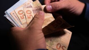 Notas de cinquenta reais sendo contadas.