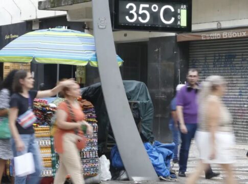 Imagem mostra um termômetro de rua mostrando a temperatura em 35º C com pessoas caminhando ao redor
