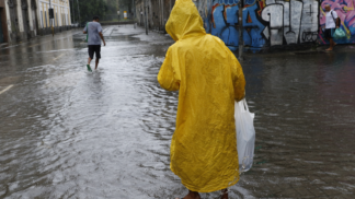 Homem caminha em rua alagada devido a chuva forte
