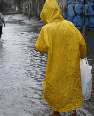 Homem caminha em rua alagada devido a chuva forte