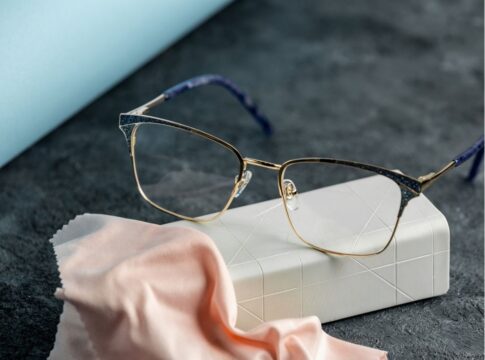 Óculos em cima de uma mesa com pano microfibra.