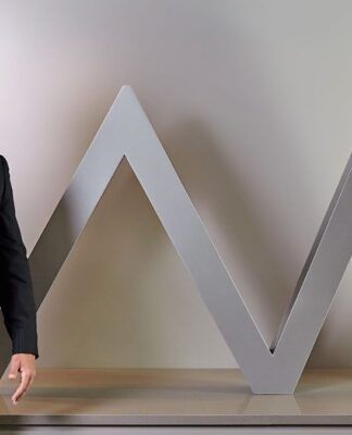 Daniel Vorcaro figura à frente do logo do seu banco vestido de terno e gravata