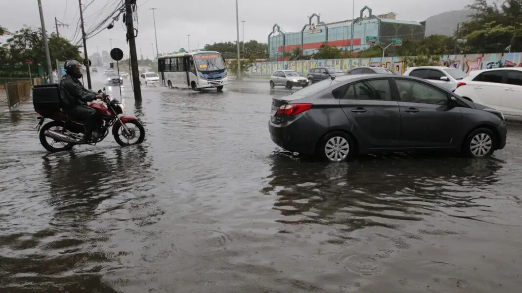 Carro preso em uma avenida alagada. Água está quase cobrindo o todo o pneu.