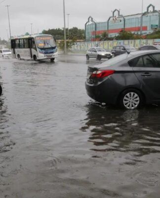 Carro preso em uma avenida alagada. Água está quase cobrindo o todo o pneu.