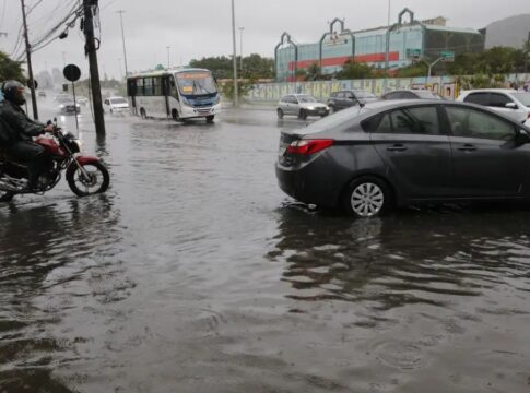 Carro preso em uma avenida alagada. Água está quase cobrindo o todo o pneu.