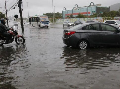 Carro preso em uma avenida alagada. Água está quase cobrindo o todo o pneu.