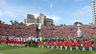 Os times de Palmeiras e Flamengo estão perfilados, com seus uniformes, para o hino nacional no gramado