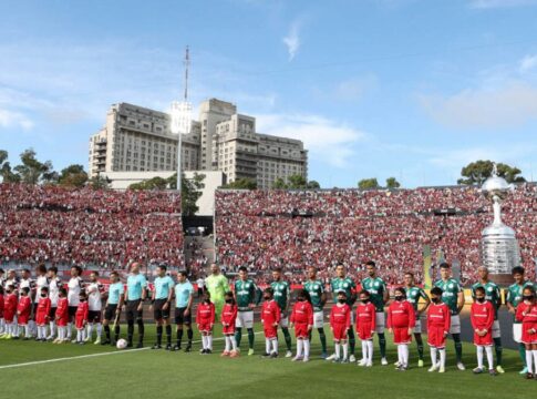 Os times de Palmeiras e Flamengo estão perfilados, com seus uniformes, para o hino nacional no gramado