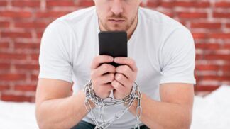 Homem sentado segurando celular com correntes nas mãos