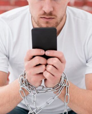 Homem sentado segurando celular com correntes nas mãos