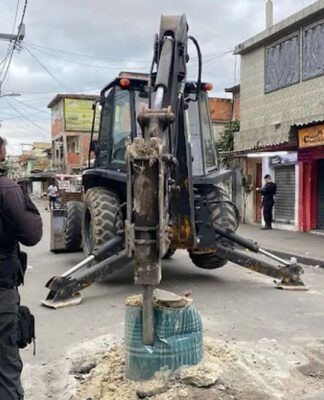 Trator desbloqueia rua enquanto policial observa