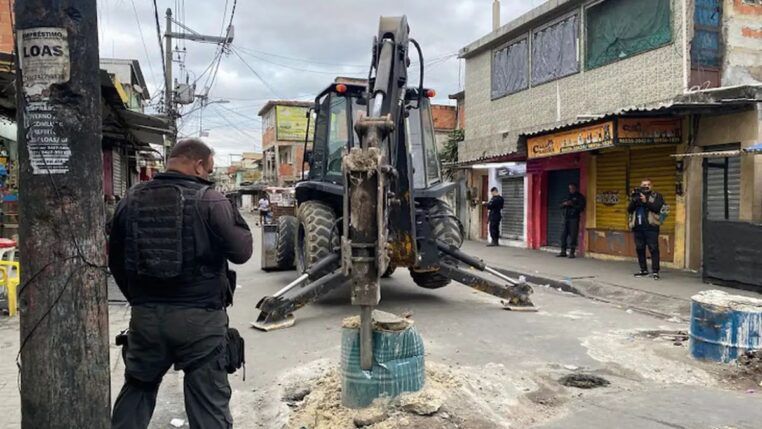 Trator desbloqueia rua enquanto policial observa