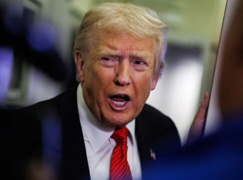 Close up de Trump usando terno azul, gravata vermelha e falando em tom enérgico