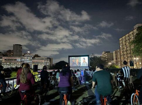 Pessoas pedalando bicicletas enquanto assistem um filme em um telão
