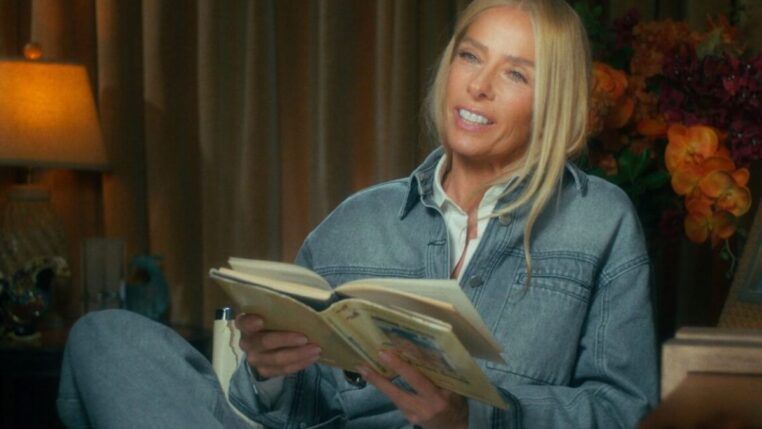 Adriane Galisteu em seu documentário segurando livro que ela escreveu na época da morte do piloto