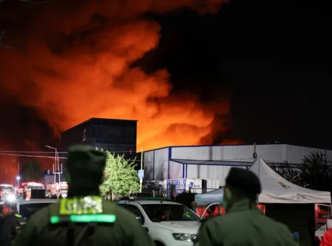 Policiais e bombeiros observam chamas de incêndio em edifício de parque industrial em Ezeiza, na Argentina