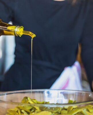 Em imagem ilustrativa, cozinheira(o) prepara alimento ultilizando azeite