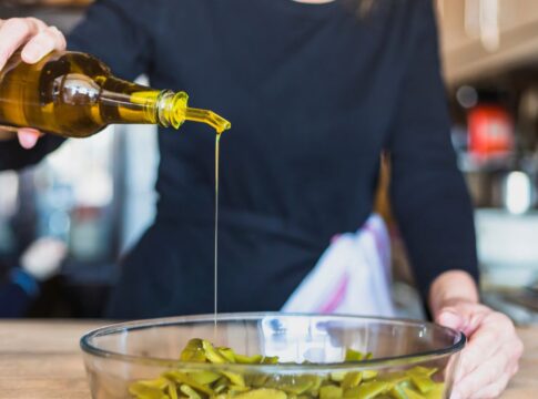 Em imagem ilustrativa, cozinheira(o) prepara alimento ultilizando azeite