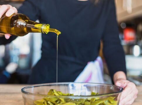 Em imagem ilustrativa, cozinheira(o) prepara alimento ultilizando azeite