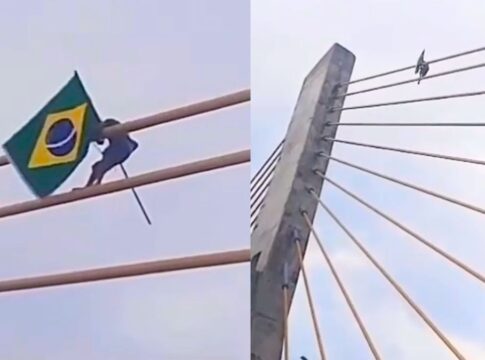 Imagem mostra um homem fincando uma bandeira do Brasil no alto de uma ponte estaiada, entre o Maranhão e Piauí
