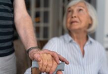 Em imagem ilustrativa, idosa recebe auxílio de um cuidador.