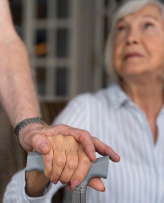 Em imagem ilustrativa, idosa recebe auxílio de um cuidador.