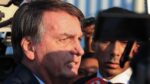 Esta é um close-up lateral do ex-presidente brasileiro Jair Bolsonaro em um ambiente externo, provavelmente falando ou respondendo a jornalistas.
